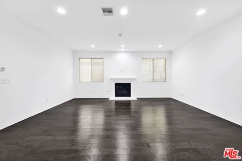 an empty room with wooden floor and fireplace