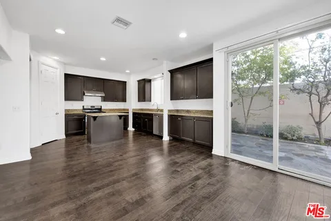 a kitchen with stainless steel appliances granite countertop a stove top oven a sink and a refrigerator