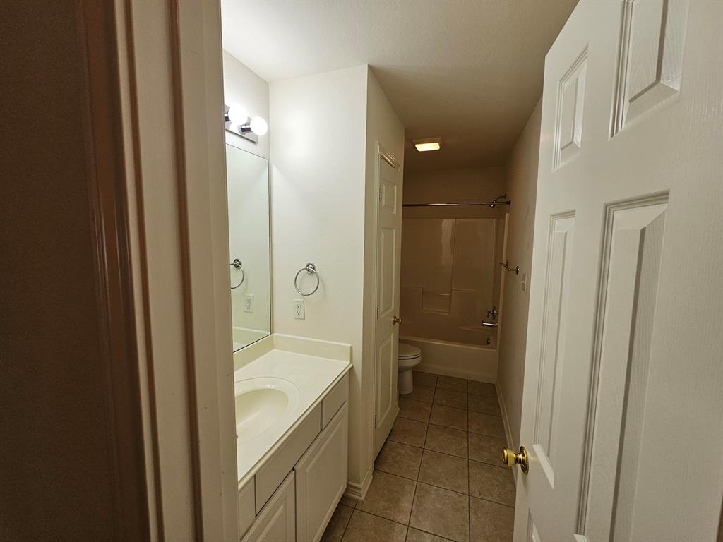 1521 Rice Road, Unit Z101 Tyler, TX 75703 - Photo 20 of 25 White paneled vanity with an integrated sink, polished chrome hardware, and a framed mirror