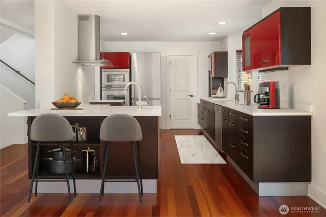 a open kitchen with stainless steel appliances granite countertop a sink dishwasher a stove a refrigerator and a dining table with wooden floor