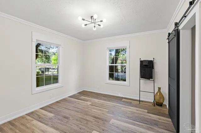 a view of an empty room with a window and wooden floor