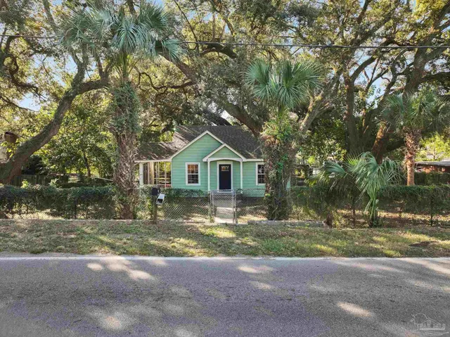 a view of a house with a yard and large tree