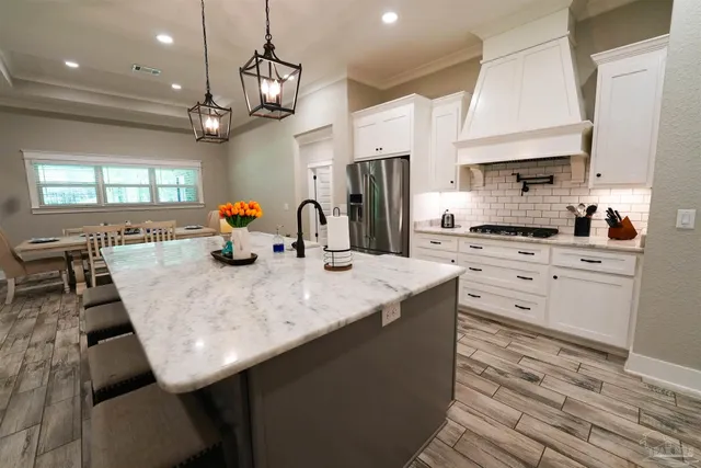 a kitchen with stainless steel appliances kitchen island granite countertop a sink a stove and a wooden cabinets