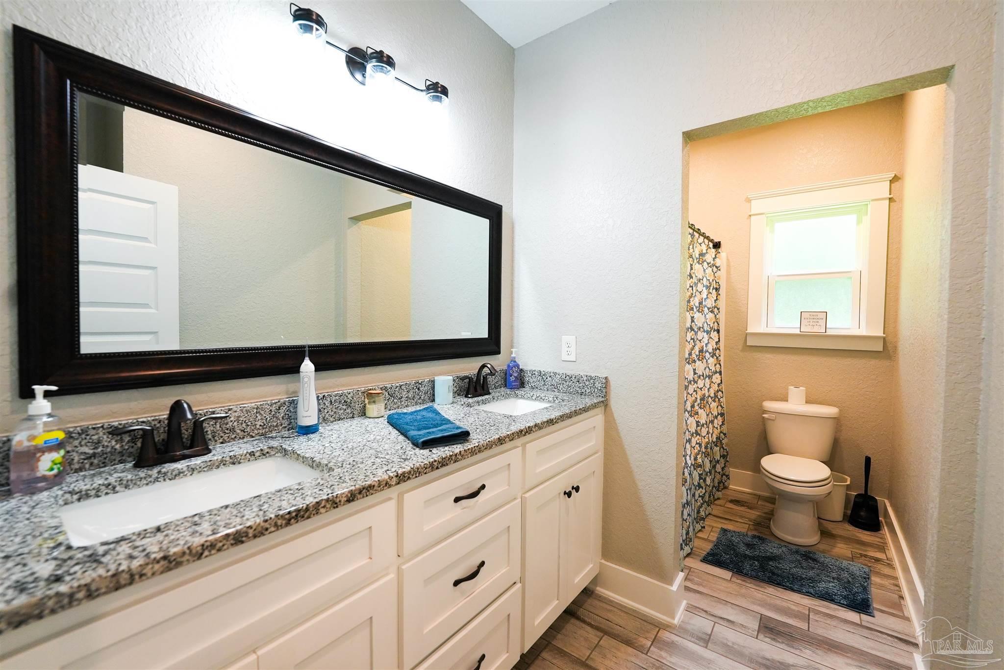 8410 Highway 97 Walnut Hill, FL 32568 - Photo 47 of 66 a bathroom with a granite countertop sink toilet and mirror