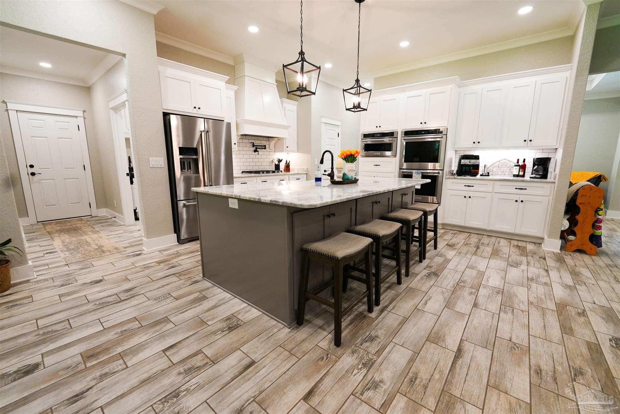 8410 Highway 97 Walnut Hill, FL 32568 - Photo 6 of 66 a kitchen with stainless steel appliances kitchen island granite countertop a refrigerator a stove top oven a sink dishwasher and white cabinets with wooden floor