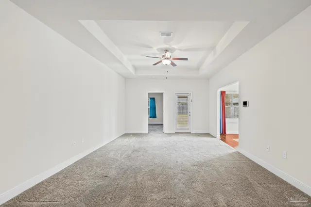 an empty room with an entryway and chandelier fan
