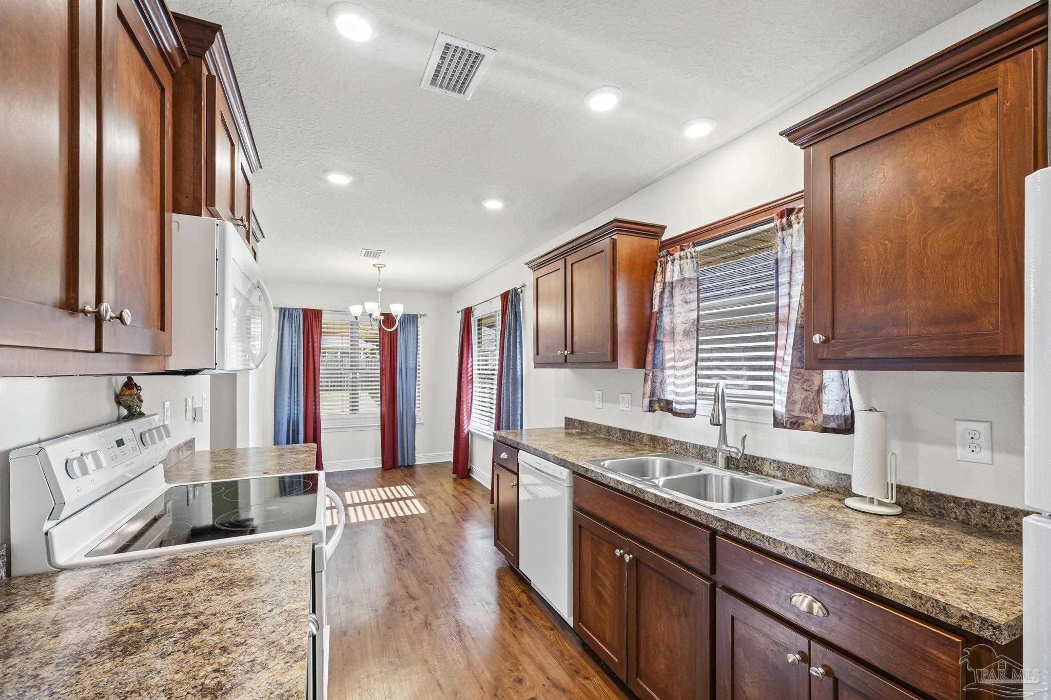4442 Fiske Street Pace, FL 32571 - Photo 24 of 44 a large kitchen with stainless steel appliances granite countertop a sink and dishwasher with wooden floor