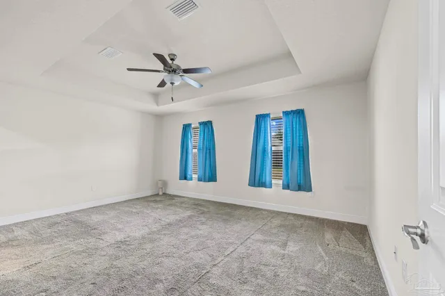 an empty room with chandelier fan and windows