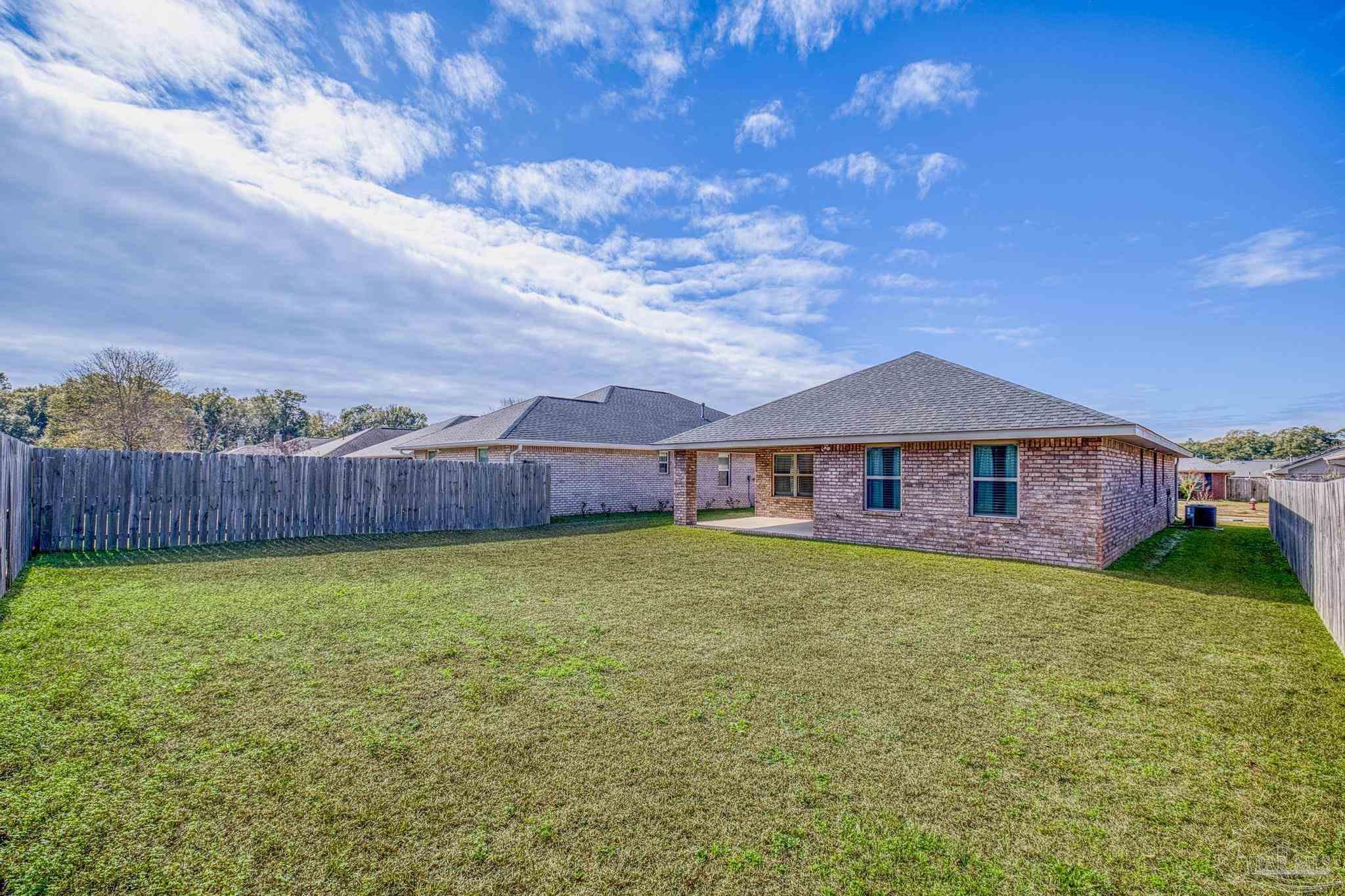 4442 Fiske Street Pace, FL 32571 - Photo 38 of 44 a view of a house with a yard potted plants and wooden fence