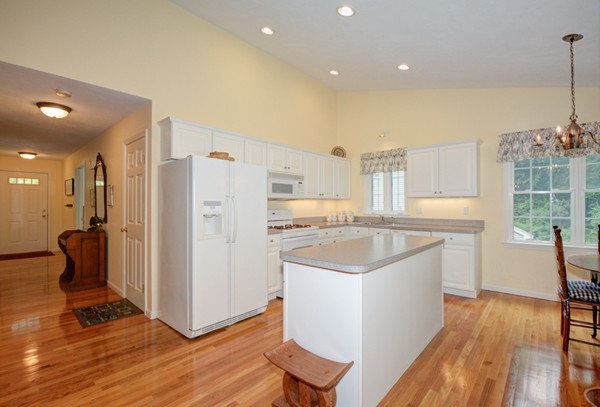 99 Stow Road, Unit 99 Boxborough, MA 01719 - Photo 2 of 27 a kitchen with a refrigerator a sink and wooden floor