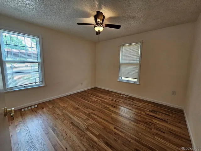 a view of empty room with wooden floor and fan
