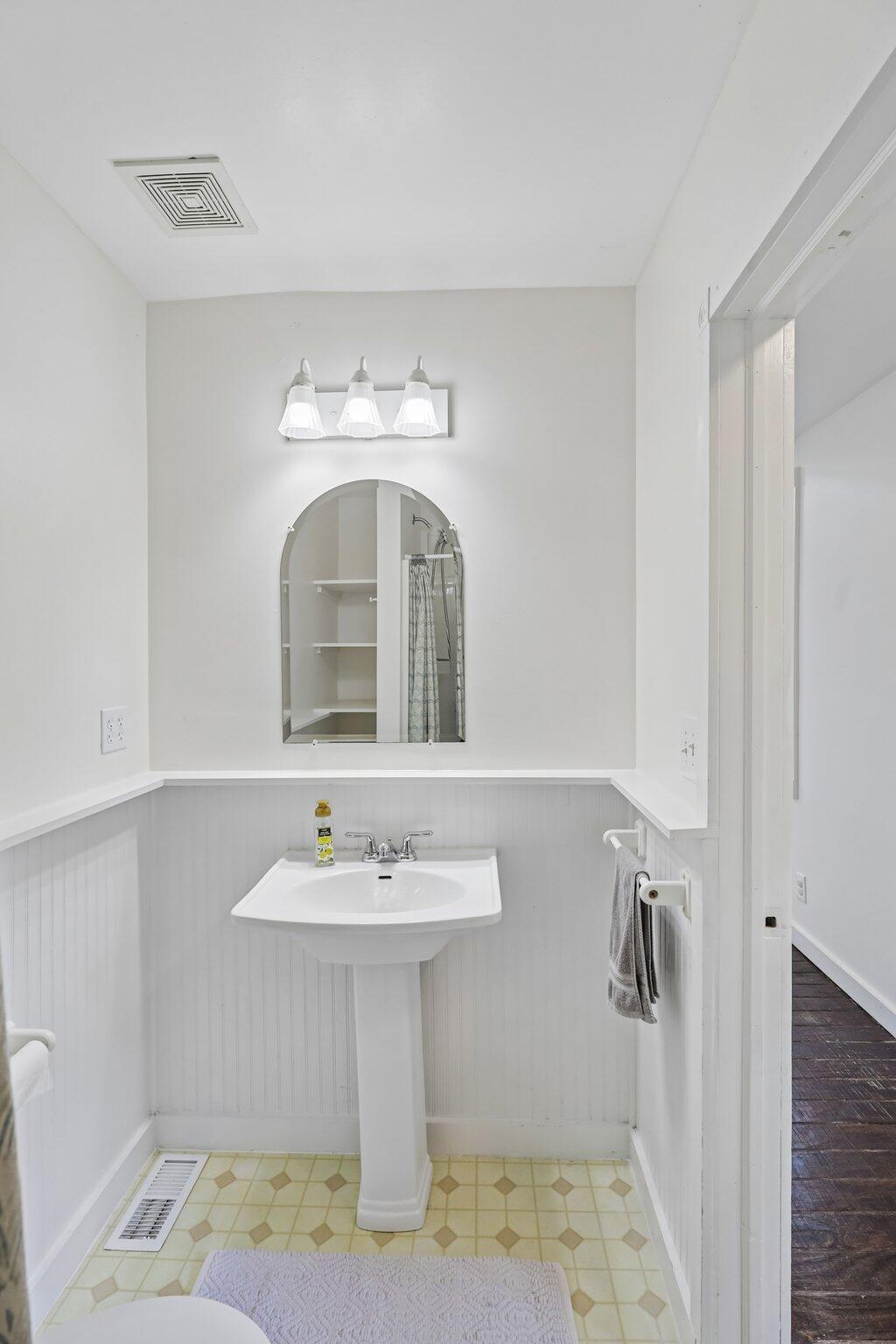 12022 Klein Road Morning View, KY 41063 - Photo 21 of 31 Pedestal sink featuring a chrome faucet, arched mirror, and beadboard wainscoting