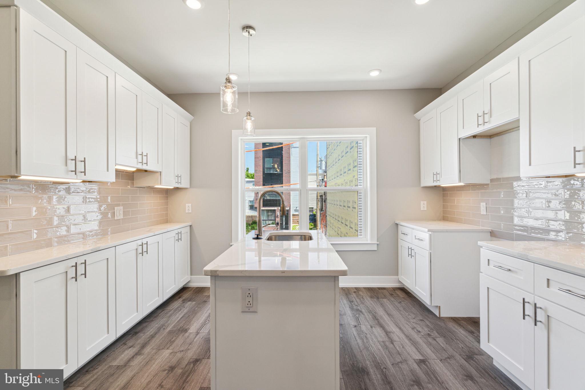 a large kitchen with kitchen island wooden floors white cabinets and stainless steel appliances