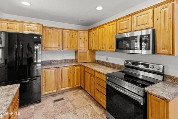 a kitchen with stainless steel appliances granite countertop a refrigerator a stove and a sink with wooden floor
