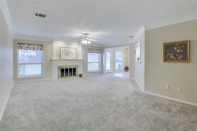 an empty room with chandelier fan and windows