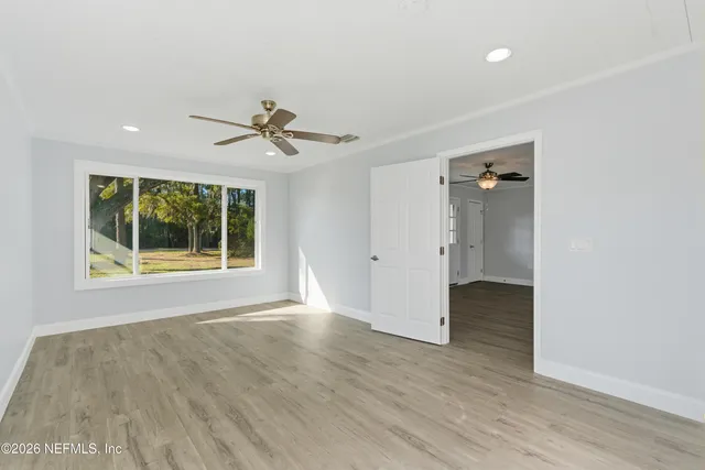 an empty room with wooden floor and a ceiling fan