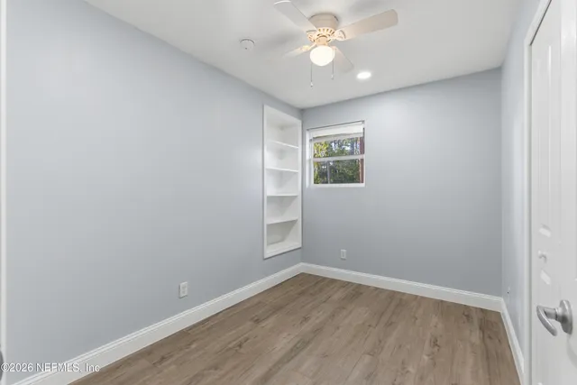 an empty room with a window and ceiling fan