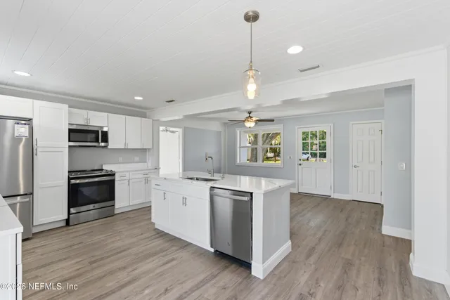 a kitchen with stainless steel appliances granite countertop a refrigerator a stove top oven a sink dishwasher and a refrigerator with wooden floor