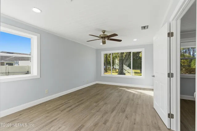 a view of an empty room with a window and wooden floor