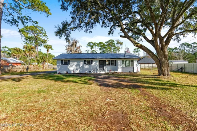 a view of house with swimming pool and a yard