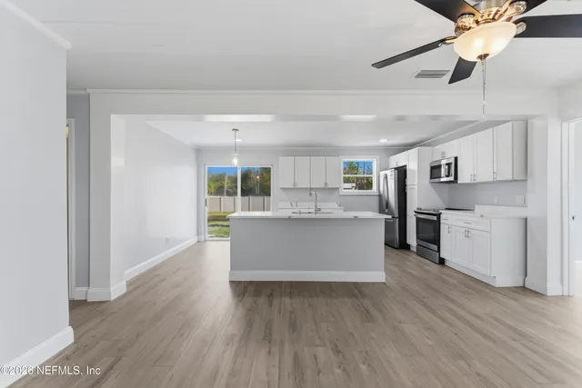 a large kitchen with a center island wooden floor and stainless steel appliances