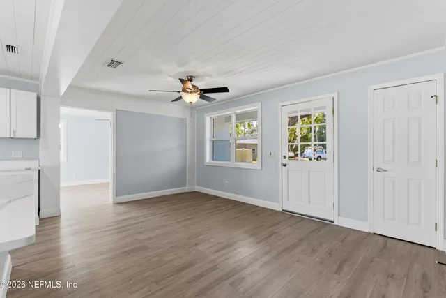 a view of an empty room with wooden floor and a window