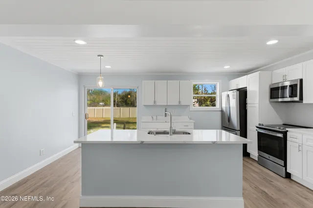 a large kitchen with kitchen island a large counter top space stainless steel appliances and cabinets