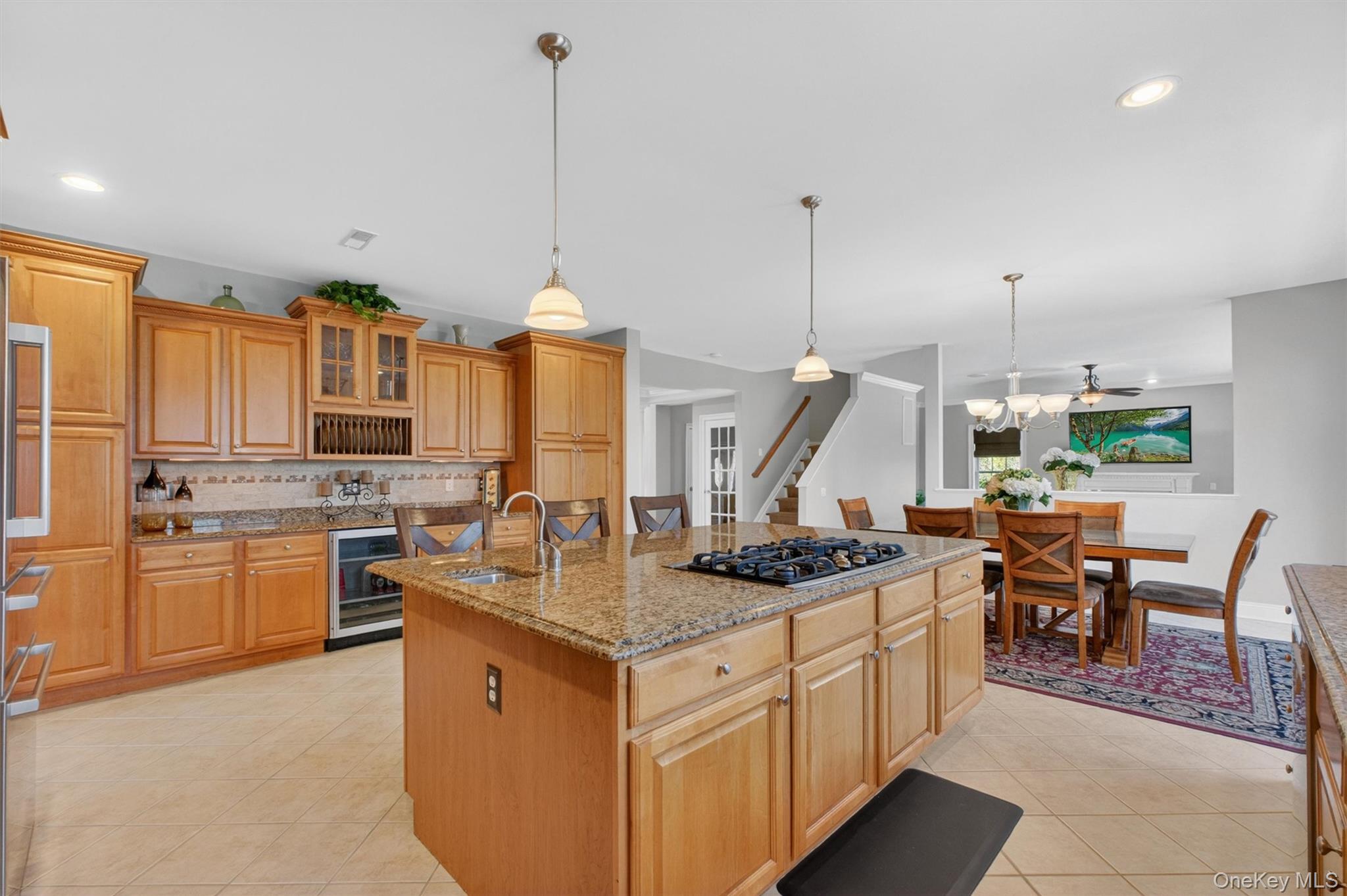 196 Country Club Road Hopewell Junction, NY 12533 - Photo 11 of 50 This magnificent kitchen is a chef’s dream, showcasing exceptional upgrades and a thoughtfully designed layout that blends elegance with everyday functionality. Custom Medallion Columbia Maple cabinetry is featured throughout, anchored by a stunning center island topped with luxurious Giallo Pallia granite and complete with a five-burner GE gas cooktop, prep sink, and seating for four. Along the window wall, an oversized feature window fills the space with natural light above a double stainless steel sink with disposal, accompanied by a Bosch dishwasher. Opposite, a dramatic wall of custom upper and lower cabinetry is framed by twin floor-to-ceiling pantry units, while an additional 8.5-foot stretch of Giallo Pallia granite provides even more prep and serving space alongside a GE Monogram beverage refrigerator. Expansive countertops offer an abundance of workspace for cooking and entertaining, while the extensive custom cabinetry ensures exceptional storage and organization. Under-cabinet lighting beautifully