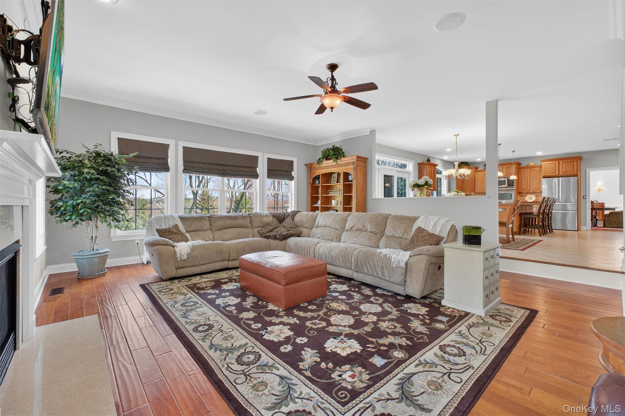 196 Country Club Road Hopewell Junction, NY 12533 - Photo 13 of 50 With an open-concept design that flows effortlessly from the magnificent chef’s kitchen and sun-filled eat-in area, the spectacular family room creates a grand yet inviting atmosphere that is truly the heart of the home. Framed by the Frenchwood slider with transom, the oversized kitchen window, and the family room’s dramatic wall of windows, the entire rear of the home is bathed in natural light and surrounded by breathtaking views. Gleaming hardwood floors, soaring ceilings, custom fabric shades, and exquisite architectural details elevate the space, while the stunning 36-inch gas fireplace with its ornate Harrisburg mantel and custom marble hearth serves as a striking focal point. Enhanced by recessed lighting, directional accent lighting, and built-in surround sound, this extraordinary setting is equally suited for elegant entertaining, festive gatherings, or quiet evenings at home, offering a seamless blend of warmth, sophistication, and timeless style.