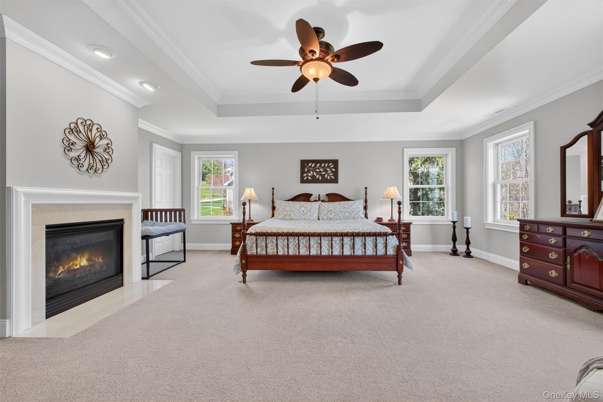 196 Country Club Road Hopewell Junction, NY 12533 - Photo 19 of 50 At one end of the suite, the grand 19' x 20' bedroom serves as a true sanctuary, featuring dramatic tray ceilings, abundant natural light, and a striking 36-inch gas fireplace with a beautifully detailed marble hearth that adds warmth, character, and timeless elegance. Two oversized custom walk-in closets—thoughtfully designed for both him and her—offer exceptional storage and organization. One closet is truly enormous, with ample room to create a boutique-style dressing room complete with custom built-ins, cabinetry, seating, or a private vanity area, while the second walk-in closet is equally spacious and well-appointed. At the opposite end of the suite, the luxurious en-suite bath is privately tucked away, completing this serene and sophisticated owner’s retreat.