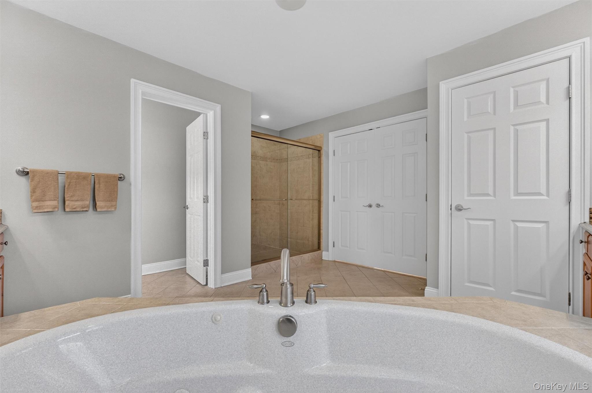 196 Country Club Road Hopewell Junction, NY 12533 - Photo 21 of 50 This exquisite primary bath is a true spa-inspired retreat, thoughtfully designed to combine everyday comfort with exceptional luxury. Beautifully coordinated granite countertops, abundant storage, upgraded fixtures, and separate his-and-her vanity cabinets provide both convenience and a sleek, streamlined look. At the center of the room, an elegant Kohler Jacuzzi tub is perfectly positioned beneath two sets of double windows that capture serene mountain views, creating an extraordinary setting for relaxation. A massive custom walk-in shower with a sleek glass enclosure adds to the retreat-like feel, while a private water closet offers added comfort and privacy. Every detail has been carefully selected to create a sophisticated and indulgent space.