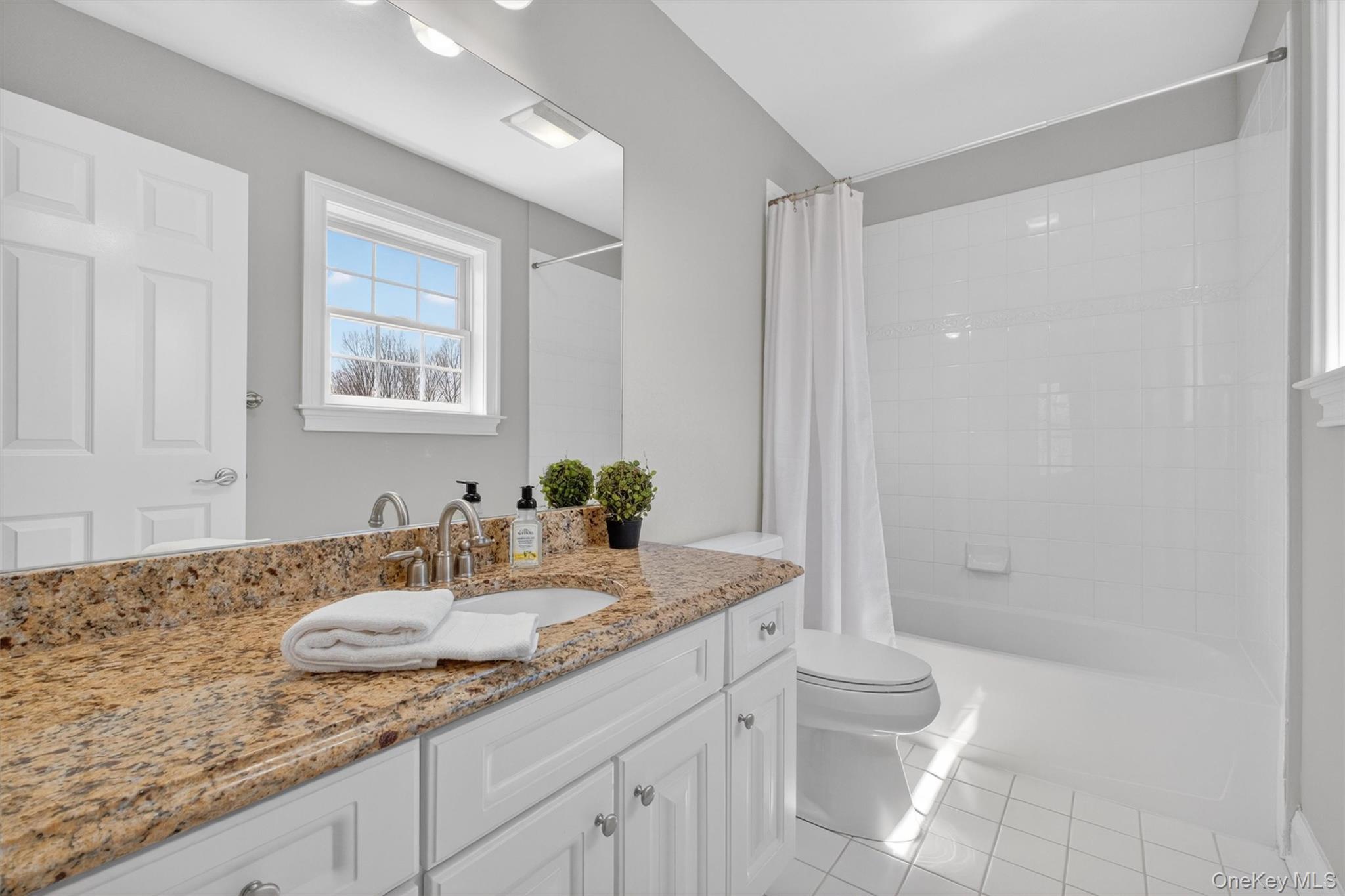 196 Country Club Road Hopewell Junction, NY 12533 - Photo 24 of 50 The private ensuite bath of this charming junior suite is beautifully designed in an exceptionally bright and neutral palette, offering a clean, timeless aesthetic. Crisp white ceramic tile surrounds the space, complemented by a spacious vanity topped with elegant St. Cecilia granite, creating both style and functionality. A white tiled tub adds to the fresh, polished look, while the overall design feels airy, refined, and welcoming. Thoughtfully appointed for comfort and convenience, this bathroom provides the perfect blend of elegance and practicality—ideal for guests, extended family, or anyone seeking a private, well-appointed retreat.