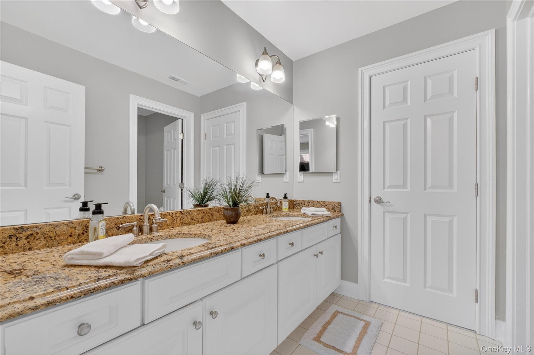 196 Country Club Road Hopewell Junction, NY 12533 - Photo 26 of 50 Connecting Bedroom #4 and the prince/princess suite, the Jack-and-Jill bath is beautifully designed for both style and function. Finished in a bright, timeless palette, the space features crisp white ceramic tile, a spacious double vanity topped with elegant St. Cecillia granite, and a clean, sophisticated look. A separate door leads to the private tub and toilet area, finished with a white tiled tub, allowing multiple people to comfortably share the space with added privacy and convenience. Ideal for family or guests, this thoughtfully designed bathroom offers the perfect blend of elegance, practicality, and everyday functionality.