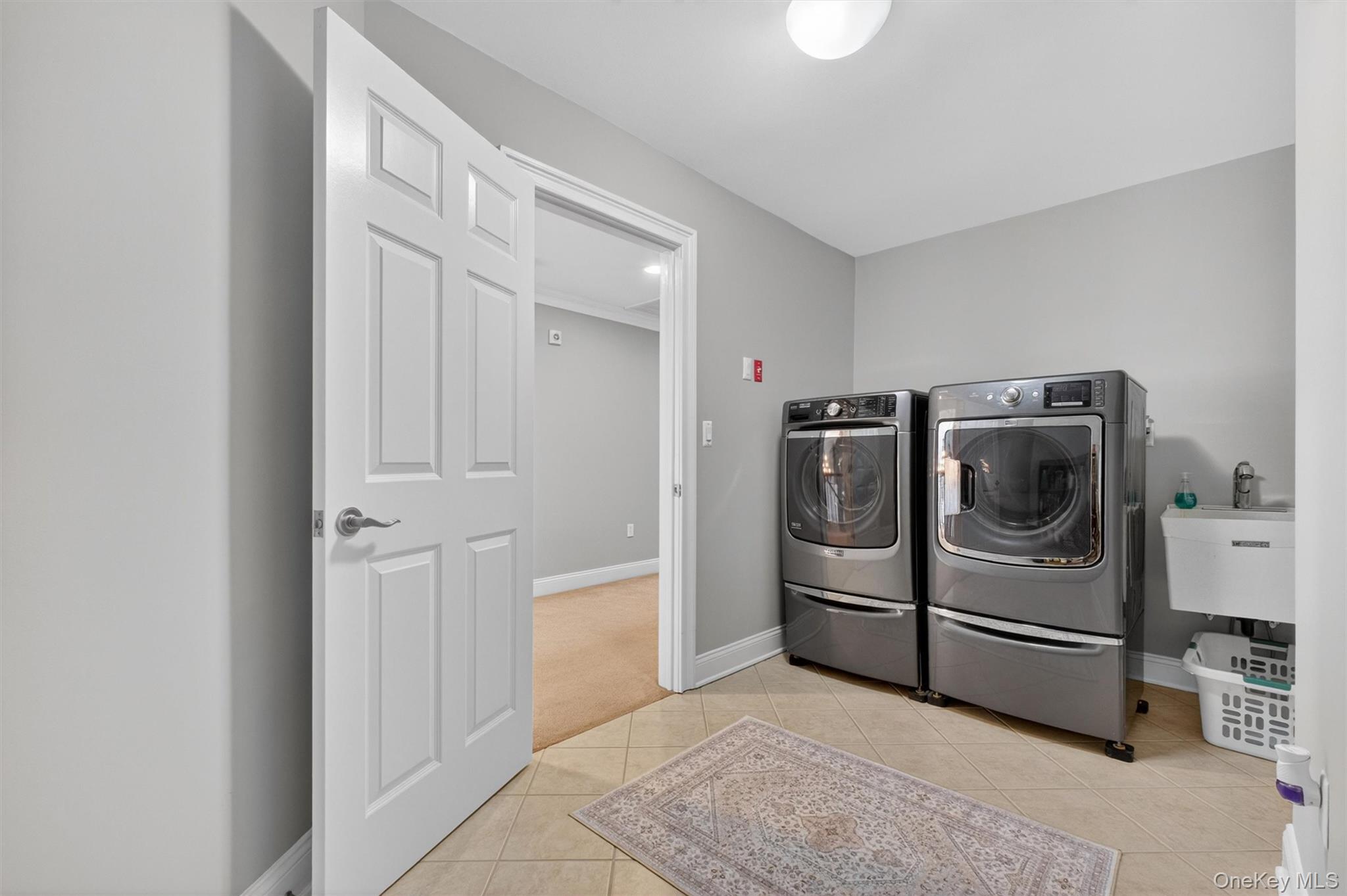 196 Country Club Road Hopewell Junction, NY 12533 - Photo 29 of 50 The oversized laundry room offers far more than everyday functionality—it’s a versatile, open-concept space that serves as a blank canvas for your vision. Similar in scale and potential to a mudroom, this expansive area invites endless possibilities, whether you envision custom cabinetry, built-in storage, folding stations, or even a multi-purpose organization hub. Equipped with newer Maytag washer and dryer units and a convenient utility sink perfect for soaking and hand-washing, the space is both practical and full of potential. With its generous layout and flexibility, this laundry room can be transformed into a beautifully designed and highly efficient extension of the home.