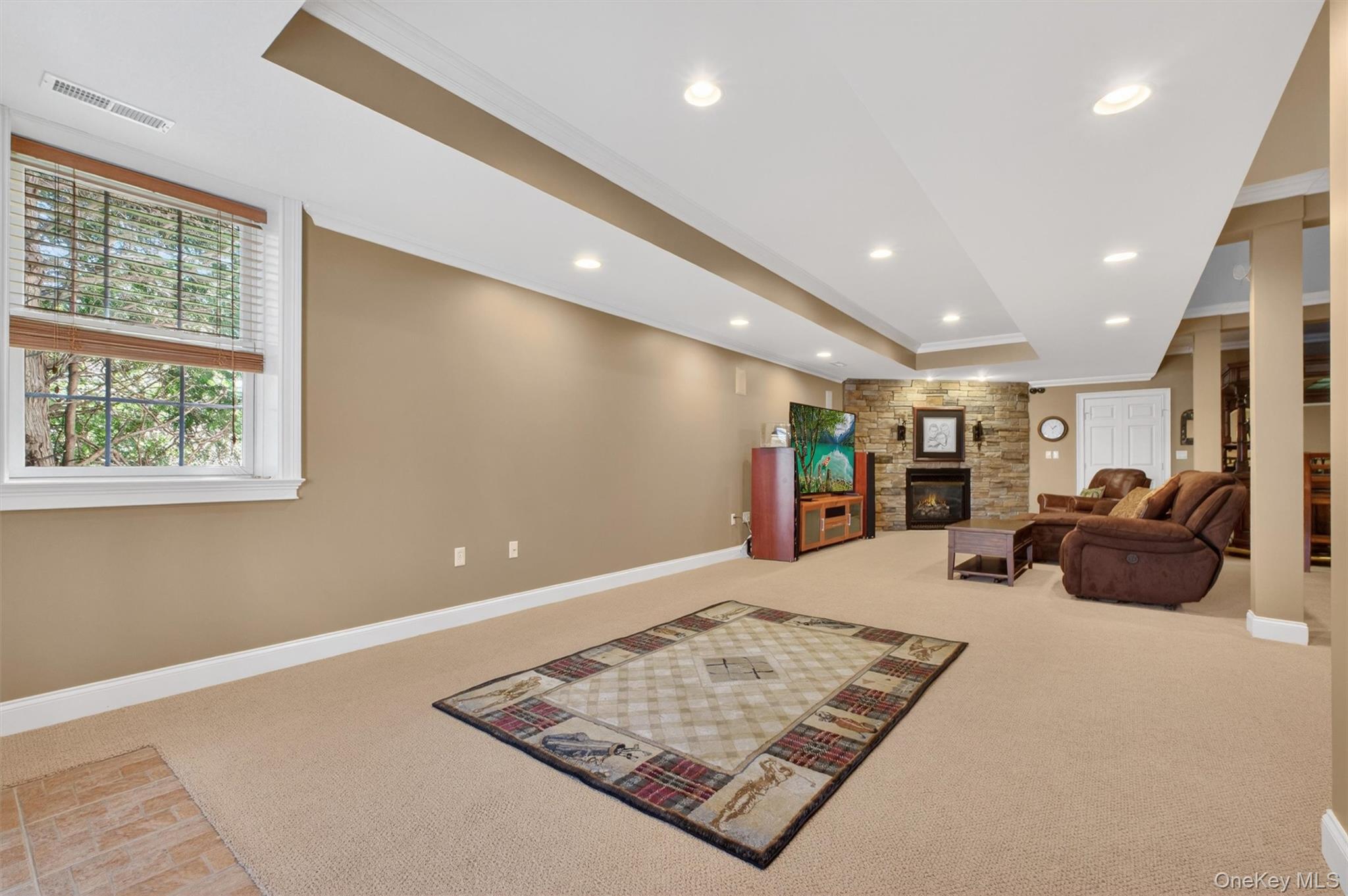 196 Country Club Road Hopewell Junction, NY 12533 - Photo 33 of 50 Entering from the lower patio, you’re welcomed into an exceptional basement retreat where the former billiards area opens seamlessly to a stylish bar and expansive living space anchored by a striking stone fireplace and beautifully appointed wine room—an entertainer’s dream. The open-concept layout flows effortlessly into a generous media and lounge area, perfect for movie nights, game days, or hosting guests, while still offering a dedicated space for billiards and recreation. Thoughtfully designed for both relaxation and versatility, this impressive lower level provides the ideal setting for entertaining or accommodating extended family with comfort, privacy, and ease.