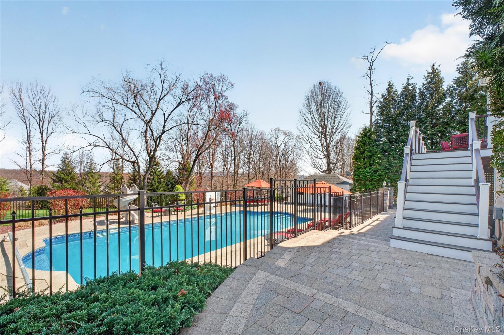 196 Country Club Road Hopewell Junction, NY 12533 - Photo 38 of 50 As you approach from the driveway toward the rear of the property, the experience unfolds like an arrival at your own private resort. Ahead, the expansive Trex deck draws your eye, offering elevated access and a stunning preview of what lies beyond. Just steps further, the entire outdoor oasis reveals itself—an impressive 22' x 48' resort-style pool, sprawling Unilock patio, inviting fire pit, and a beautifully appointed pool house, all perfectly positioned for both relaxation and grand-scale entertaining. The layout is seamless, the setting is private, and the ambiance is nothing short of extraordinary. This breathtaking outdoor retreat is truly the cherry on top of an already spectacular property—where every day feels like a getaway.