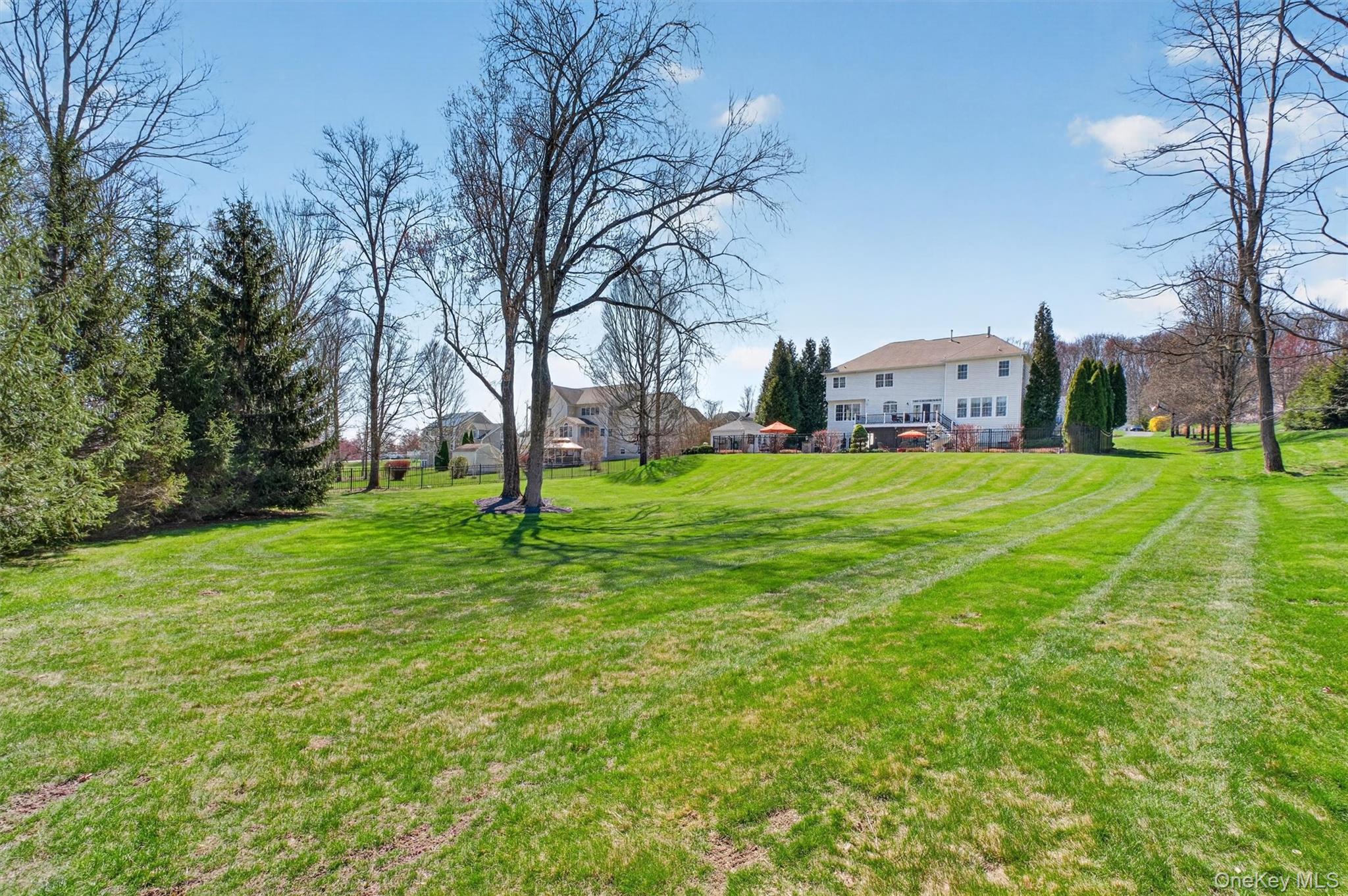 196 Country Club Road Hopewell Junction, NY 12533 - Photo 44 of 50 This property offers convenient side yard access to the expansive rear grounds and stunning Unilock patio, making outdoor living and entertaining effortless. Beyond the pool area, an additional open lawn provides a perfect, safe space for outdoor activities—ideal for swings, tag, or games of baseball and soccer—thoughtfully set apart from the gated pool area for added peace of mind. The meticulously maintained landscape is supported by a 10-zone irrigation system, ensuring the lush lawn, professional plantings, and beautifully manicured flowerbeds and trees remain vibrant year-round. The current owners have taken exceptional pride in the home, with all grounds professionally maintained, the exterior freshly power washed, windows professionally cleaned, and the pool fully opened and ready for immediate enjoyment—offering a truly turnkey outdoor experience.