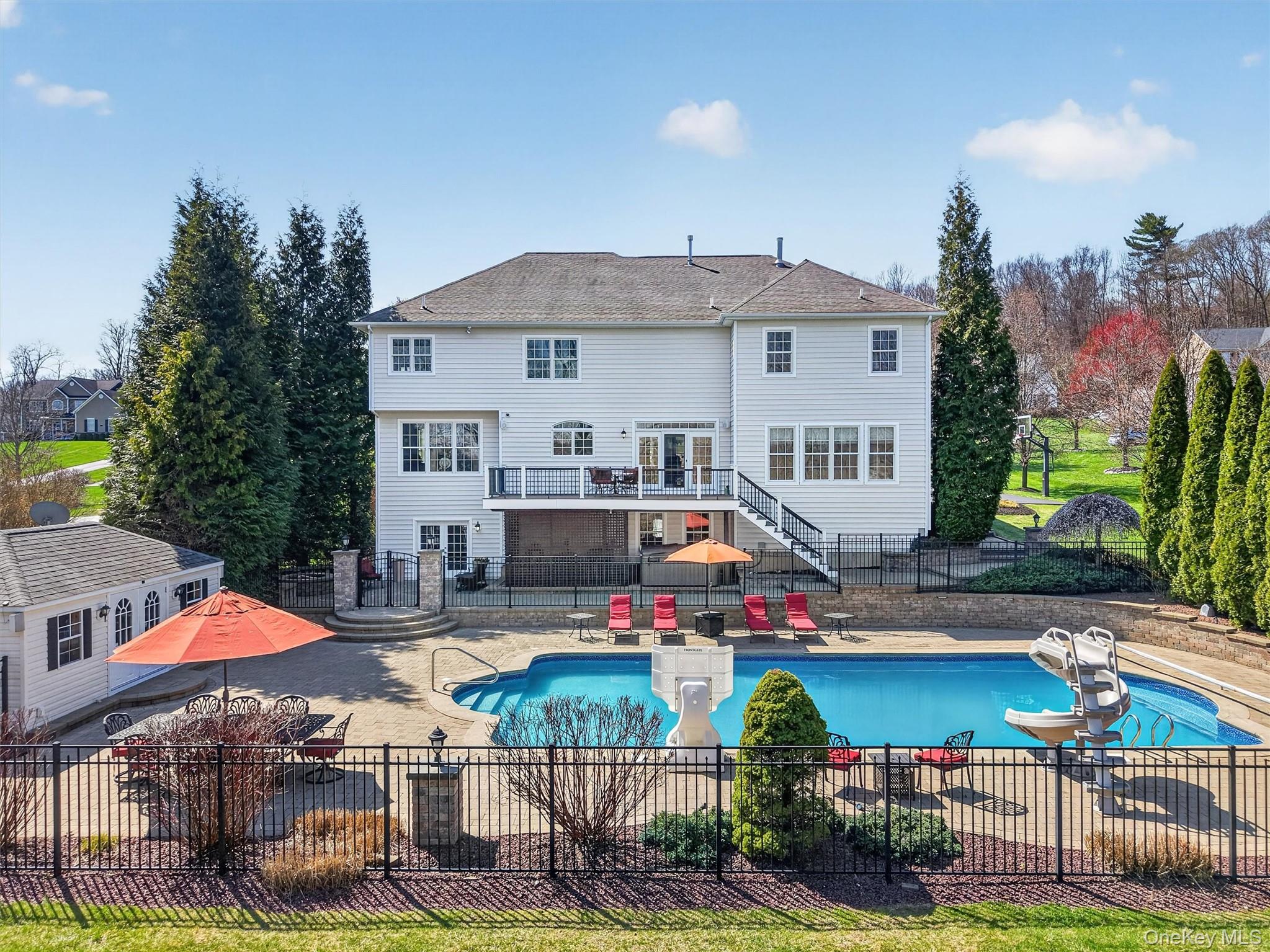 196 Country Club Road Hopewell Junction, NY 12533 - Photo 45 of 50 Enjoy complete backyard privacy with a massive rear yard designed for exceptional outdoor living, entertaining, and relaxation. Anchored by a stunning 22' x 48' in-ground swimming pool—complete with heater, new pump, new salt cell, new filter, and a full automation package for convenient iOS control—this outdoor space is truly resort-like. A 12' x 20' pool house, hardwired for electric and audio, enhances the experience, while a fully integrated sound system with 10 wired external speakers (including pool rock, pool house, deck, under-deck, and fire pit placements) creates the perfect atmosphere throughout. Whether hosting large gatherings or enjoying quiet moments, the expansive yard offers endless opportunities for recreation and future customization. Perfectly blending privacy with sweeping scenic surroundings, this home delivers the tranquility of a secluded retreat while still embracing the open, majestic beauty of the highly sought-after Legends neighborhood.