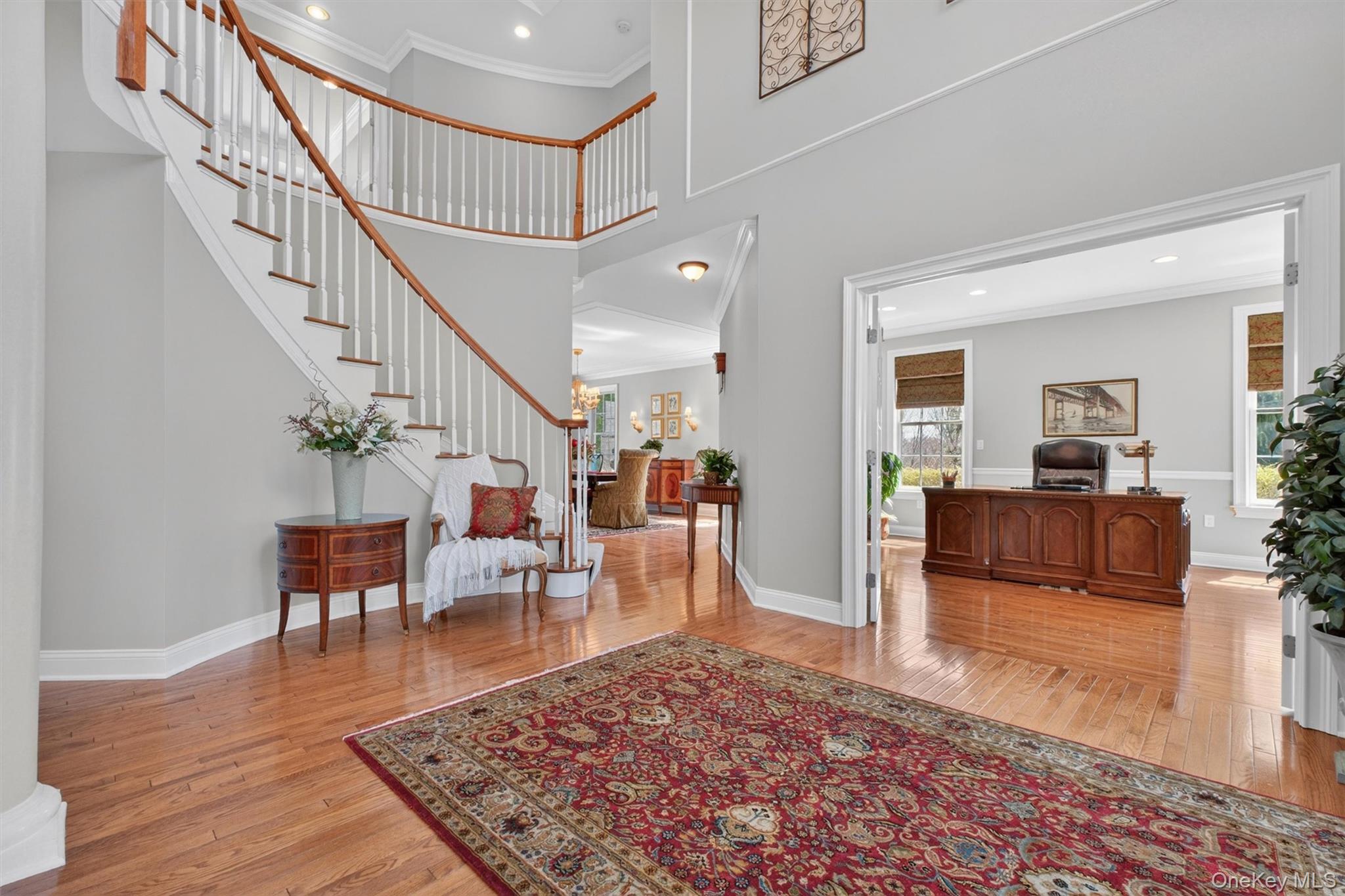 196 Country Club Road Hopewell Junction, NY 12533 - Photo 5 of 50 Equally impressive, the view from the grand two-story reception hall reveals the home’s beautifully balanced design, with sightlines extending toward the elegant formal dining room and oversized executive office. These refined spaces offer the perfect setting for both intimate gatherings and productive work-from-home living. The reception hall also serves as the central hub connecting to the upper level, where generously sized bedrooms and well-appointed baths await. This striking vantage point highlights the home’s grand scale, thoughtful layout, and seamless integration of formal and casual living spaces—delivering both sophistication and functionality throughout.