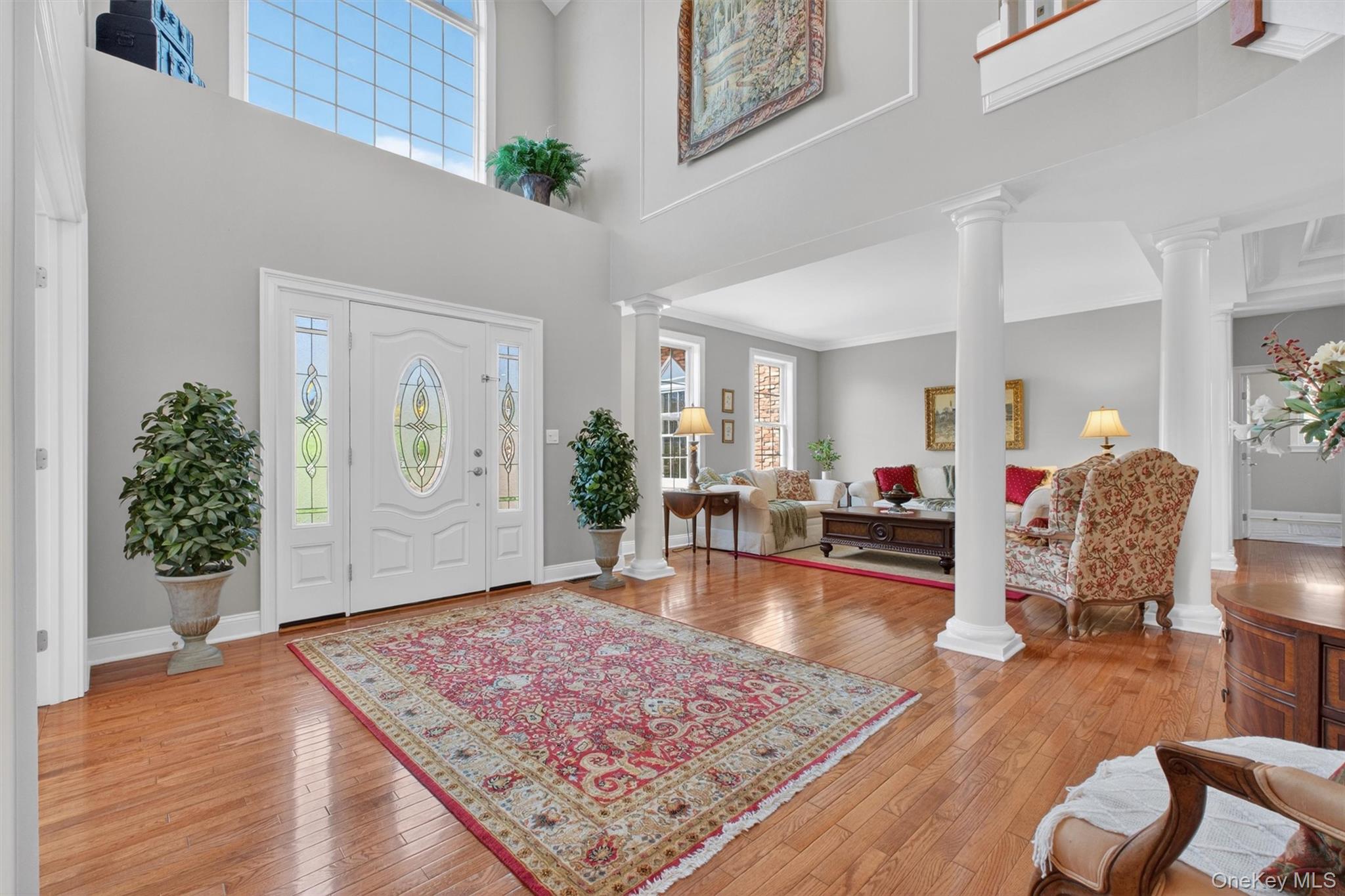 196 Country Club Road Hopewell Junction, NY 12533 - Photo 8 of 50 A true statement of grandeur, this breathtaking view from the dining room into the dramatic two-story reception hall showcases the home’s show-worthy elegance at its finest. Your eyes are immediately drawn upward to the spectacular oversized feature window set above the grand front glass door with elegant sidelights, flooding the space with natural light and accentuating the soaring ceilings. This stunning architectural focal point creates an unforgettable first impression, capturing the scale, sophistication, and undeniable magnificence that defines this exceptional home.