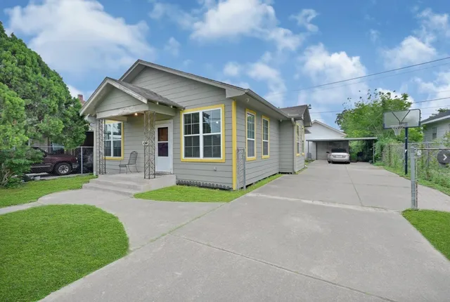 a view of a house with a yard and large tree