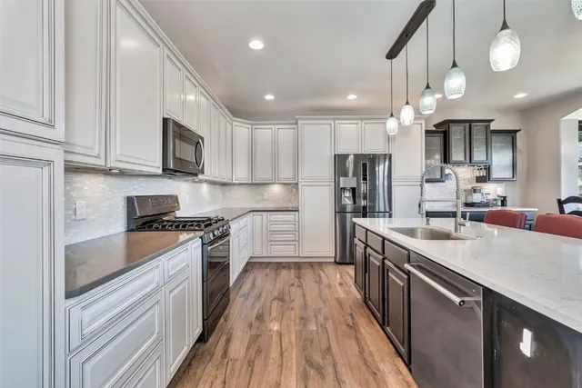 a large kitchen with stainless steel appliances granite countertop a lot of counter space a sink and cabinets