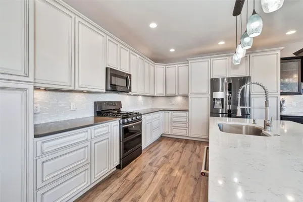 a kitchen with stainless steel appliances granite countertop a stove sink and cabinets