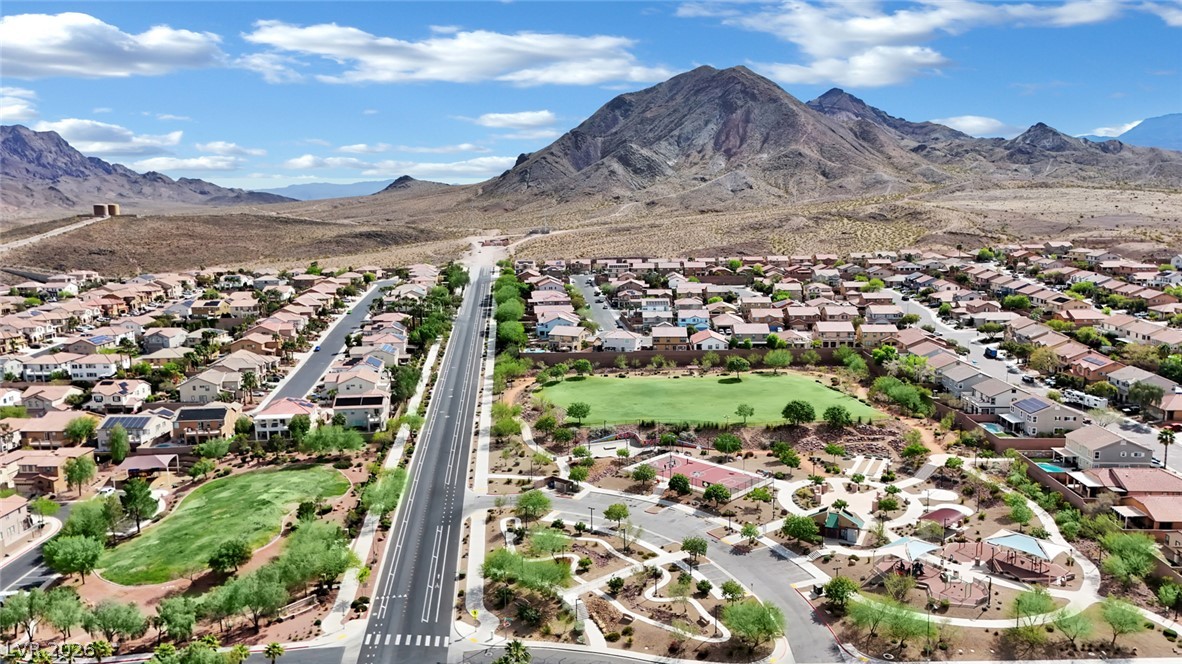 646 Monument Point Street Henderson, NV 89002 - Photo 42 of 44 A vibrant neighborhood with desert landscaping, a green park, and a mountain backdrop.