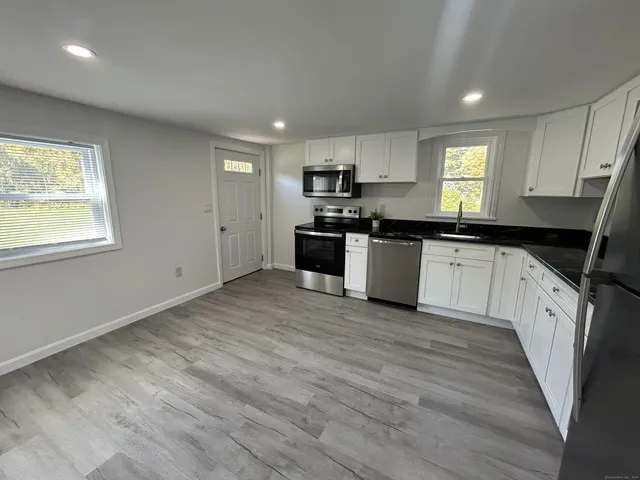 a kitchen with granite countertop a stove top oven sink and cabinets