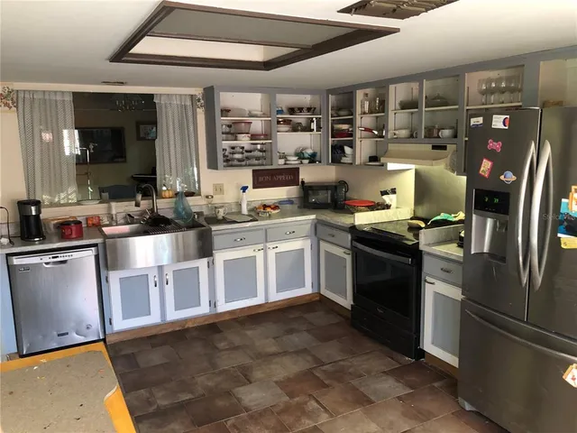 a kitchen with stainless steel appliances granite countertop a refrigerator a sink a stove top oven a counter space and cabinets