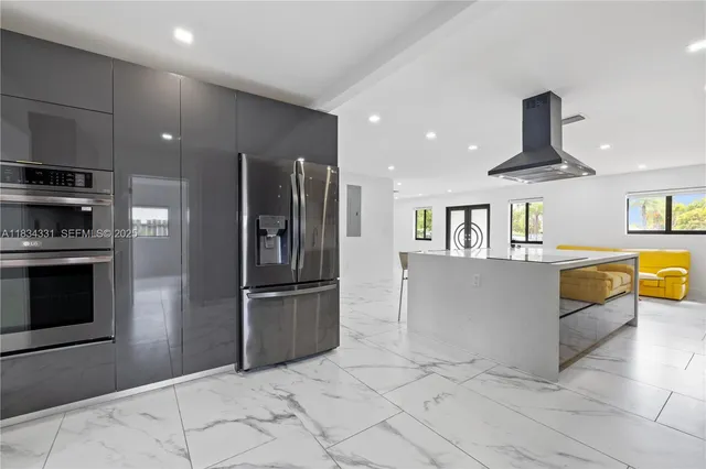 a large kitchen with stainless steel appliances granite countertop a sink a stove and a refrigerator