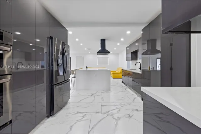 a large kitchen with stainless steel appliances a large counter top a stove and a refrigerator