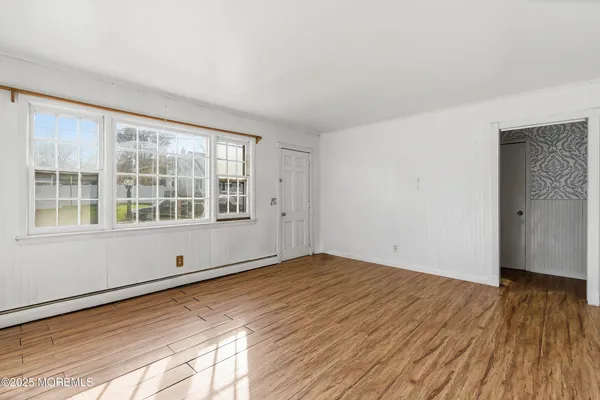 a view of empty room with wooden floor and fan