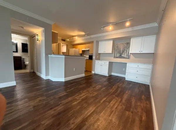a open kitchen with white cabinets and wooden floor